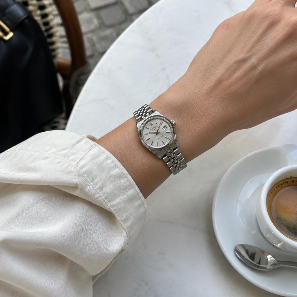 Illustrative lifestyle photo of a silver watch worn at a café